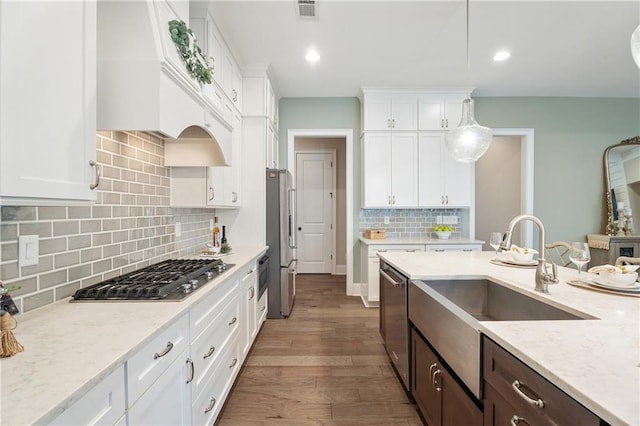 kitchen featuring appliances with stainless steel finishes, dark hardwood / wood-style flooring, pendant lighting, light stone countertops, and white cabinets