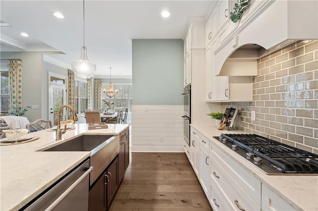 kitchen with stainless steel appliances, pendant lighting, white cabinets, and light stone counters