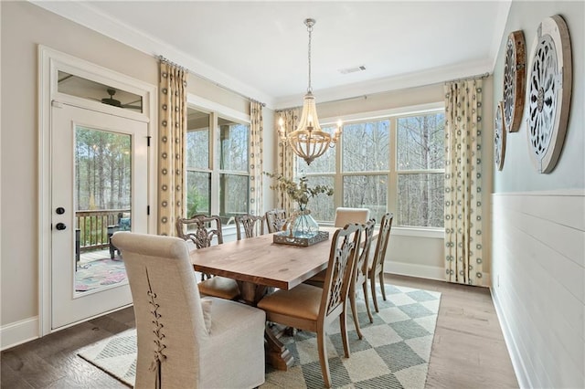 dining room with an inviting chandelier, crown molding, and light wood-type flooring