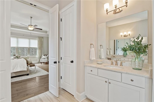 bathroom with crown molding, vanity, ceiling fan with notable chandelier, and hardwood / wood-style floors