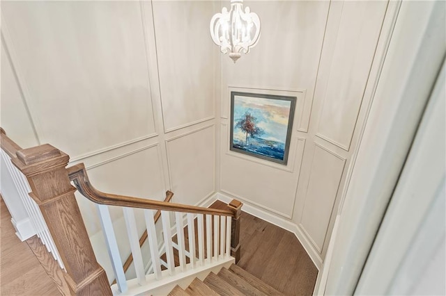 staircase with hardwood / wood-style floors and a notable chandelier