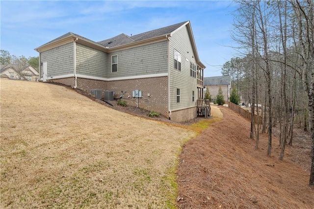 view of side of home with central AC and a lawn