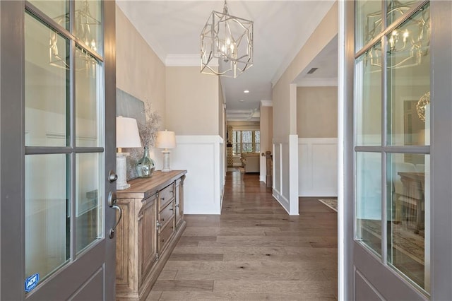 corridor with a notable chandelier, ornamental molding, and light hardwood / wood-style floors