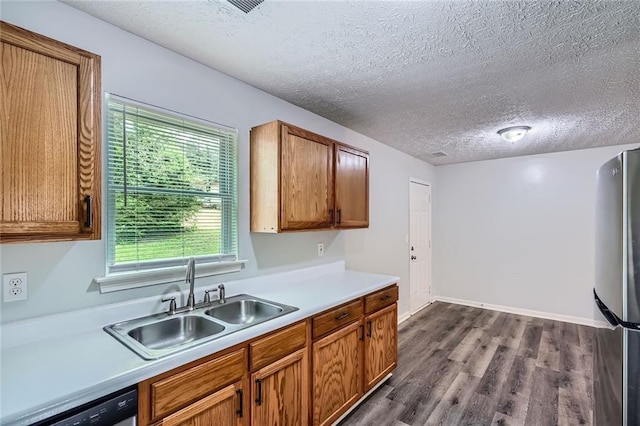 kitchen featuring freestanding refrigerator, dishwashing machine, light countertops, a sink, and dark wood finished floors