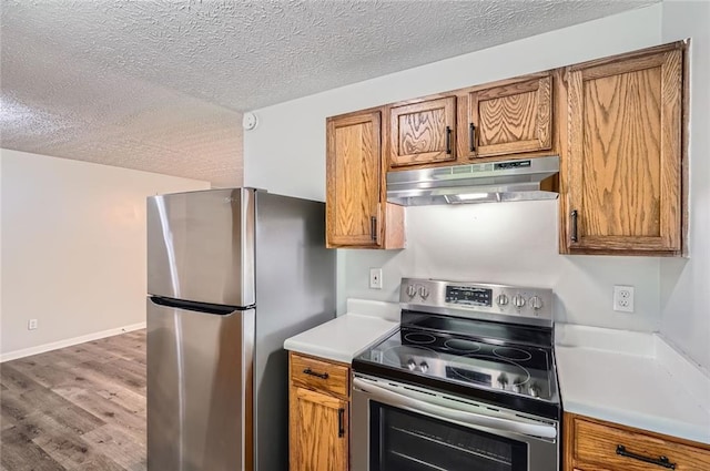 kitchen featuring a textured ceiling, appliances with stainless steel finishes, under cabinet range hood, and brown cabinets