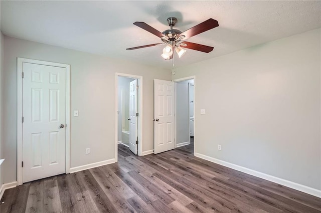unfurnished bedroom featuring baseboards, ensuite bathroom, wood finished floors, and ceiling fan