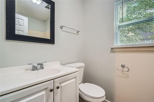 half bathroom featuring toilet, a textured ceiling, visible vents, and vanity