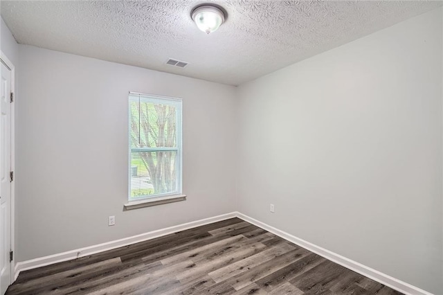 unfurnished room with visible vents, a textured ceiling, baseboards, and dark wood-style floors