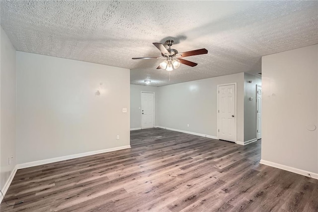 empty room featuring baseboards, a ceiling fan, a textured ceiling, and dark wood finished floors