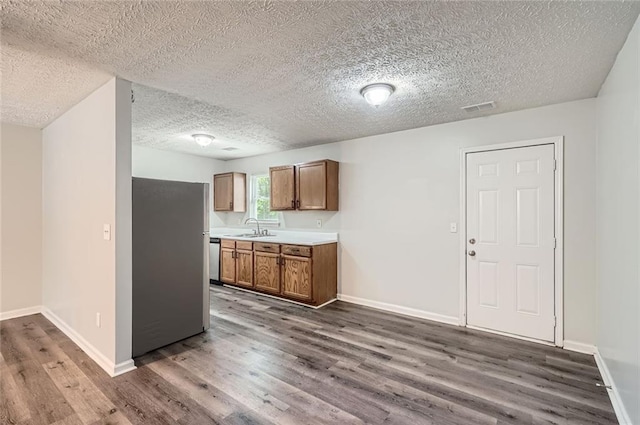 kitchen with visible vents, dark wood-type flooring, brown cabinets, a sink, and appliances with stainless steel finishes