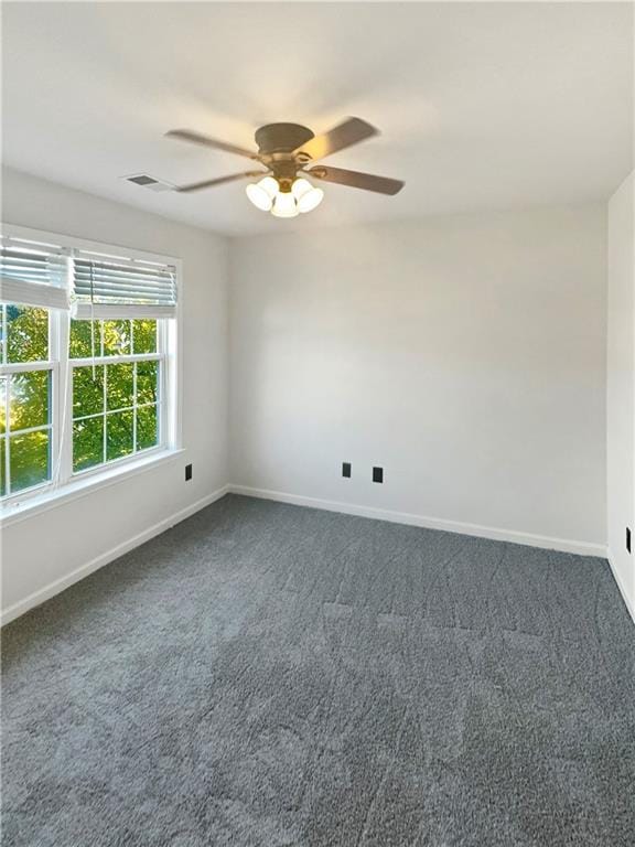 spare room with ceiling fan and dark colored carpet