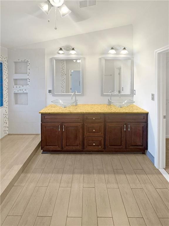 bathroom with ceiling fan, vaulted ceiling, vanity, and hardwood / wood-style floors