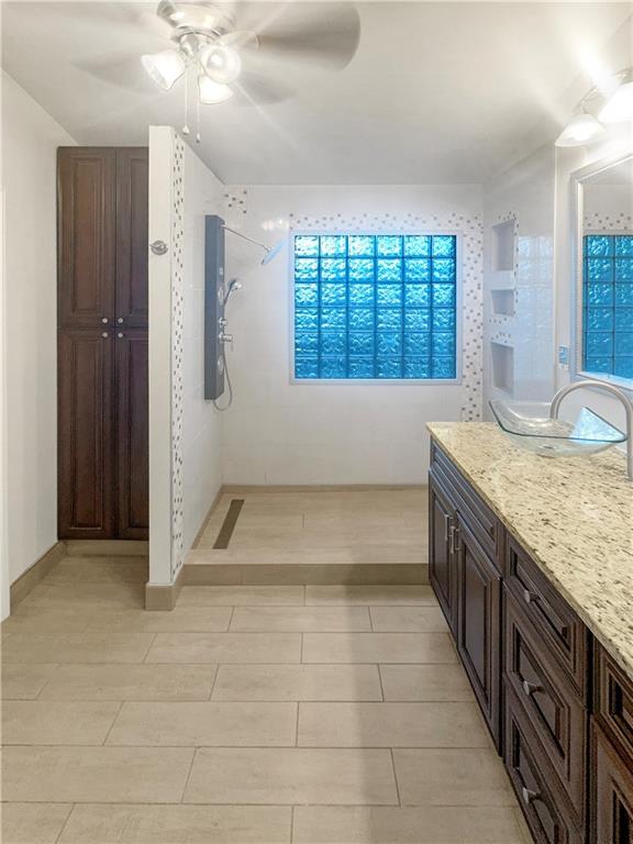 bathroom featuring a tile shower, ceiling fan, and vanity