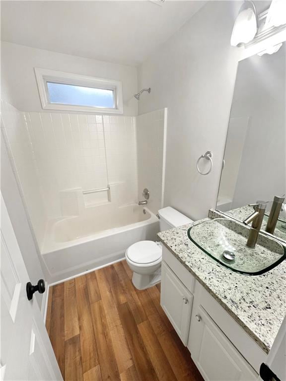 full bathroom featuring washtub / shower combination, hardwood / wood-style floors, vanity, and toilet