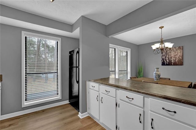 3906 Cedar Cir Unit 3906, Tucker, GA 30084 - kitchen featuring dark countertops, a chandelier, white cabinets, light wood finished floors, and a textured ceiling