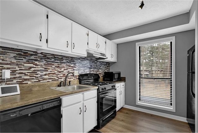 3906 Cedar Cir Unit 3906, Tucker, GA 30084 - kitchen with black appliances, under cabinet range hood, wood finished floors, white cabinetry, and backsplash