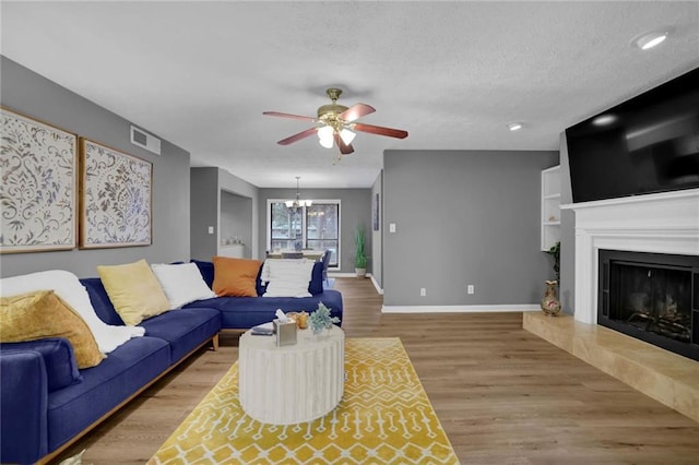 3906 Cedar Cir Unit 3906, Tucker, GA 30084 - living room with a ceiling fan, light wood-style flooring, a chandelier, a fireplace with raised hearth, and a textured ceiling