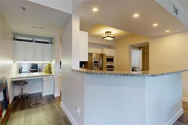 3275 Lenox Rd NE Unit 413, Atlanta, GA 30324 - kitchen with appliances with stainless steel finishes, built in desk, dark wood-style floors, white cabinets, and recessed lighting