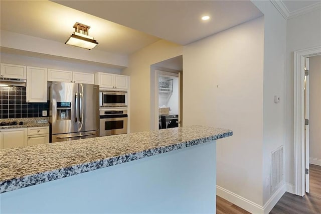 3275 Lenox Rd NE Unit 413, Atlanta, GA 30324 - kitchen featuring appliances with stainless steel finishes, under cabinet range hood, dark wood-type flooring, tasteful backsplash, and white cabinets