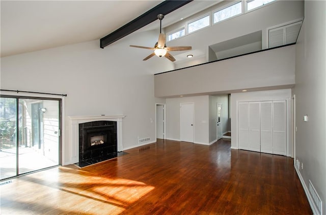 unfurnished living room featuring visible vents, dark wood finished floors, beam ceiling, and a tile fireplace