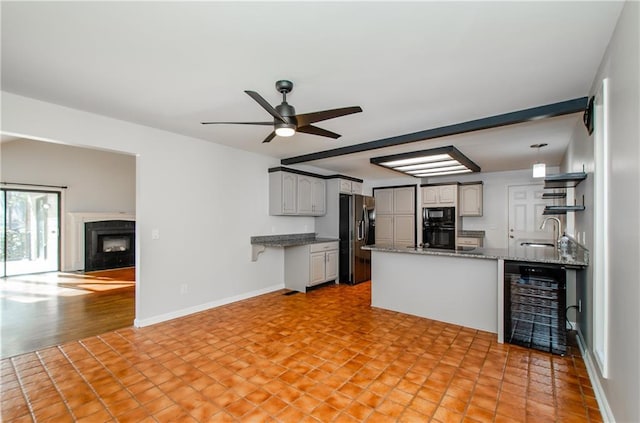 kitchen with open floor plan, black appliances, a peninsula, and a fireplace