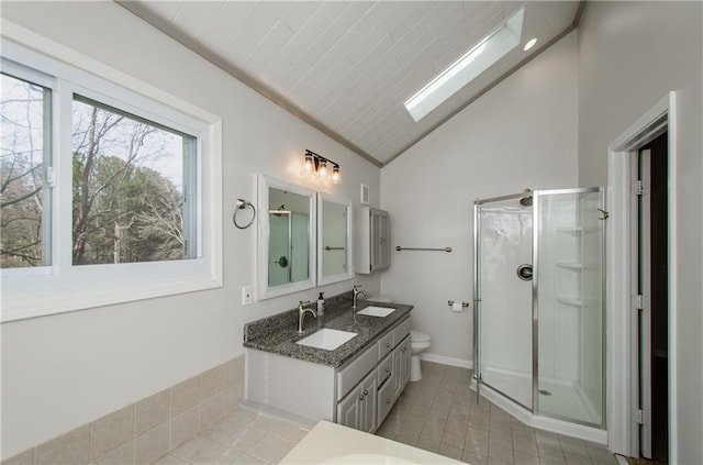 full bathroom featuring lofted ceiling with skylight, a stall shower, a sink, and double vanity