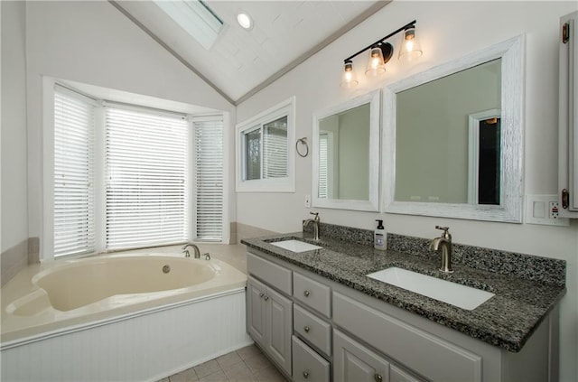 full bath featuring double vanity, a garden tub, vaulted ceiling, and a sink