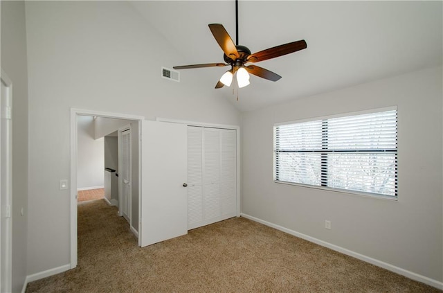 unfurnished bedroom with a closet, visible vents, light carpet, vaulted ceiling, and baseboards