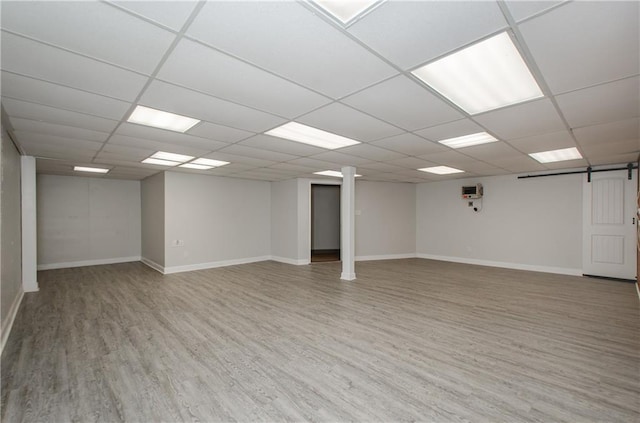 empty room featuring baseboards, a barn door, and light wood-style floors