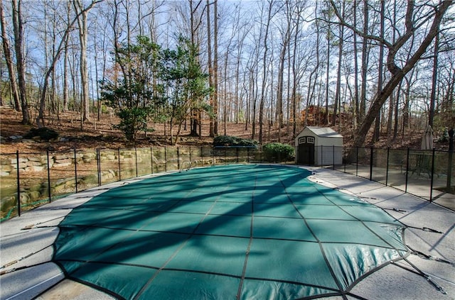 view of swimming pool featuring a storage unit, fence, a fenced in pool, and an outdoor structure