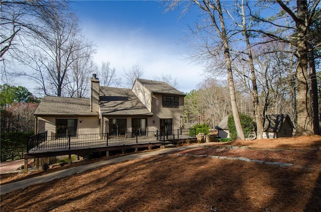 back of property featuring a chimney and a deck