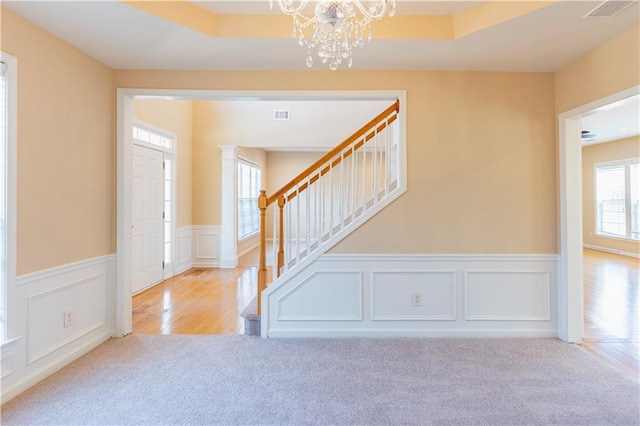 foyer entrance featuring carpet floors, stairway, visible vents, and an inviting chandelier