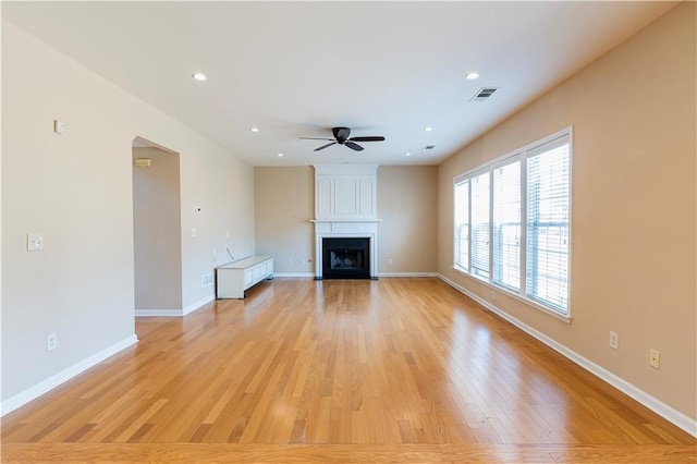 unfurnished living room with baseboards, visible vents, light wood-style floors, a fireplace, and recessed lighting