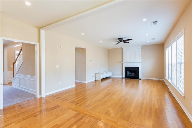 unfurnished living room featuring a fireplace, recessed lighting, visible vents, light wood-style flooring, and stairs