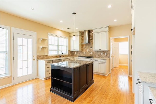 kitchen featuring open shelves, tasteful backsplash, stainless steel appliances, wall chimney range hood, and light wood-type flooring