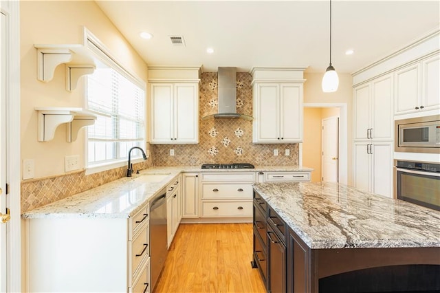 kitchen featuring visible vents, wall chimney exhaust hood, appliances with stainless steel finishes, open shelves, and a sink