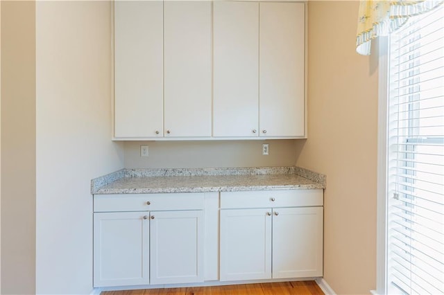 kitchen featuring light stone counters and white cabinetry