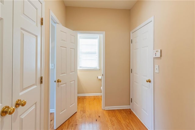 hall with light wood-style flooring and baseboards