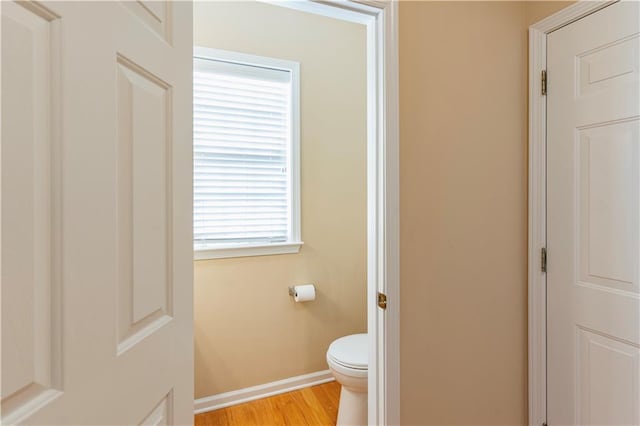 bathroom with baseboards, toilet, and wood finished floors