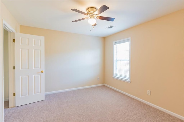 empty room featuring baseboards, visible vents, ceiling fan, and light colored carpet