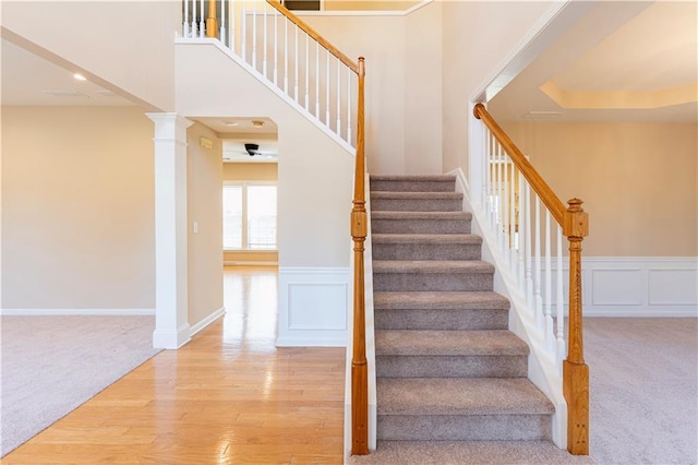 staircase featuring carpet flooring, decorative columns, and a decorative wall