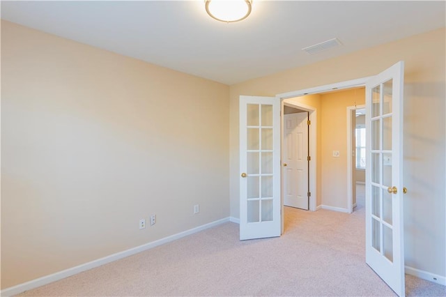 empty room with carpet floors, french doors, visible vents, and baseboards