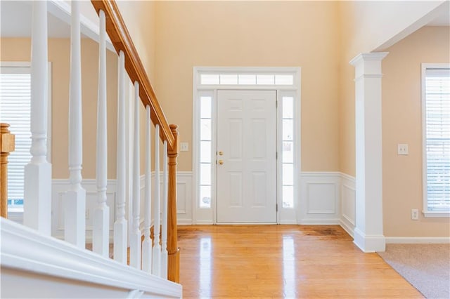 entryway with wainscoting, a decorative wall, plenty of natural light, and light wood-style floors