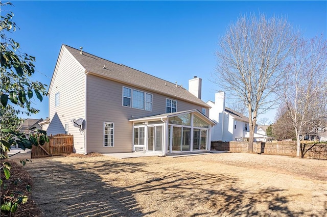 back of house with a sunroom, a patio area, a chimney, and fence