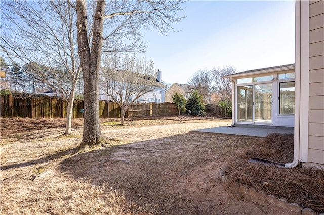 view of yard featuring a sunroom, a fenced backyard, and a patio