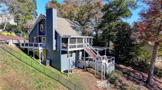 rear view of property with a deck, a lawn, cooling unit, and a sunroom