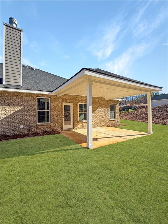 rear view of house featuring a yard and a patio area