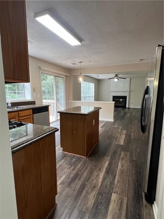 11800 Carriage Park Ln, Johns Creek, GA 30097 - kitchen featuring appliances with stainless steel finishes, a kitchen island, dark wood-style floors, a textured ceiling, and a glass covered fireplace