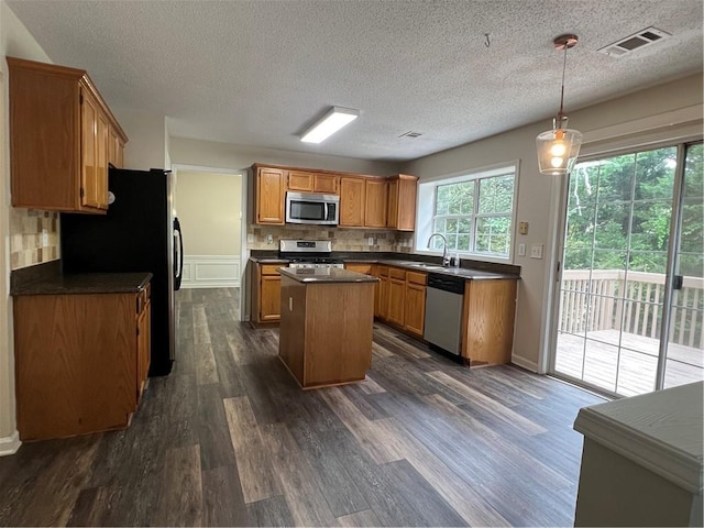 11800 Carriage Park Ln, Johns Creek, GA 30097 - kitchen with stainless steel appliances, dark countertops, a center island, dark wood finished floors, and decorative backsplash
