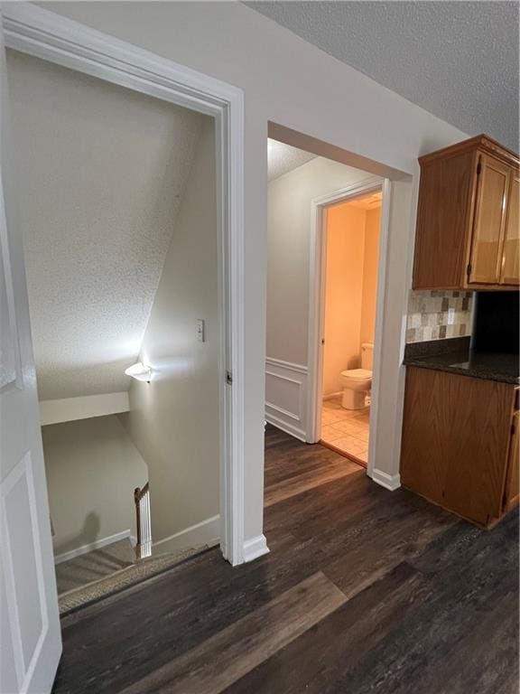 11800 Carriage Park Ln, Johns Creek, GA 30097 - kitchen featuring dark countertops, dark wood-type flooring, a textured ceiling, backsplash, and brown cabinets